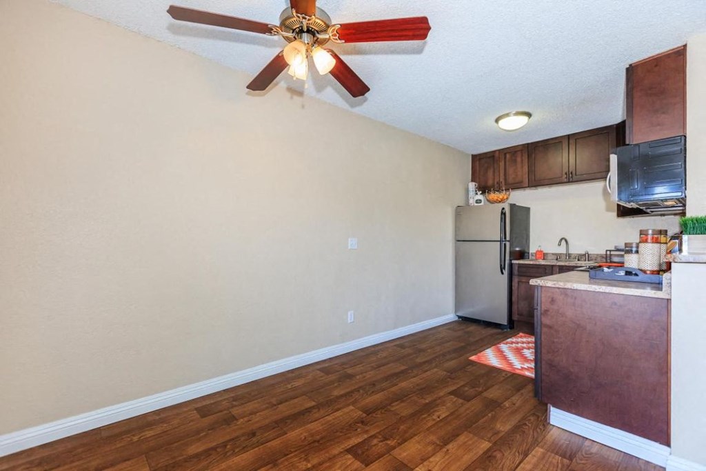 an empty kitchen with a ceiling fan and a refrigerator