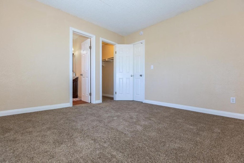 an empty living room with carpeting and white doors