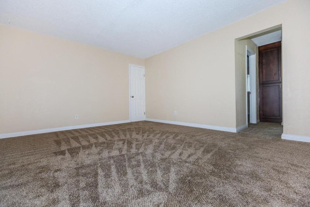 an empty living room with carpet and a door