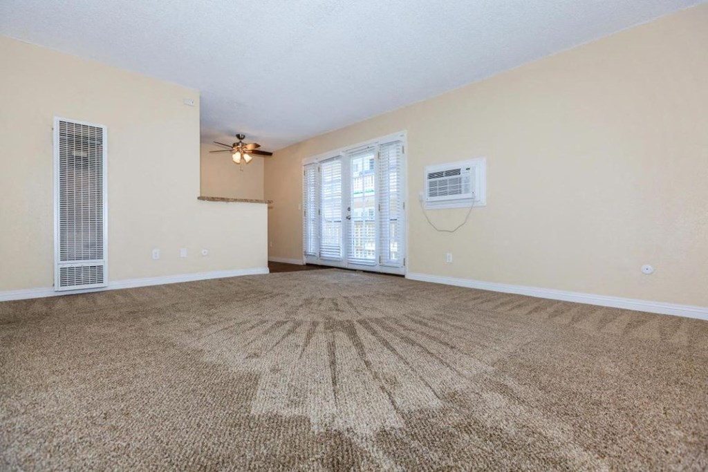 an empty living room with a ceiling fan and a window