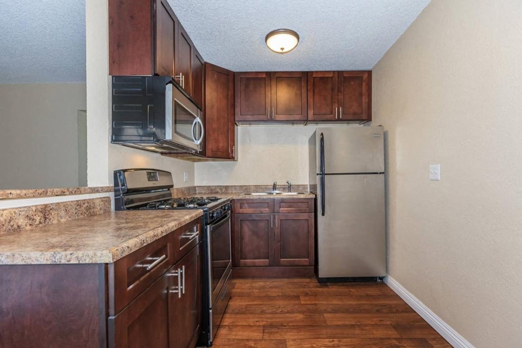 a kitchen with wooden cabinets and a stainless steel refrigerator