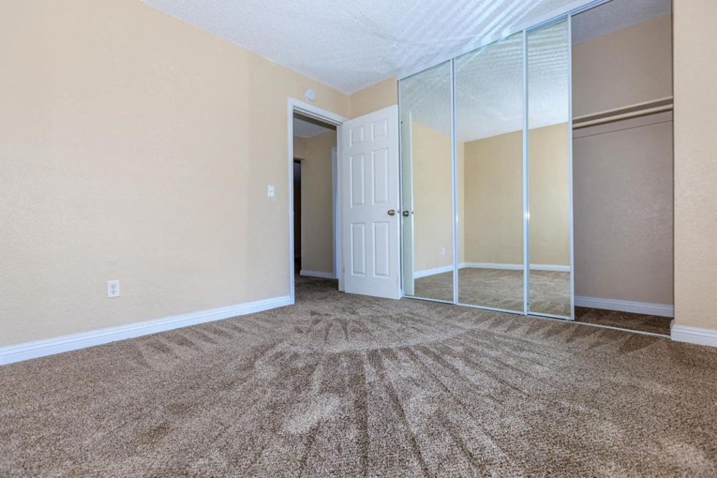 an empty living room with mirrored closet doors and carpet