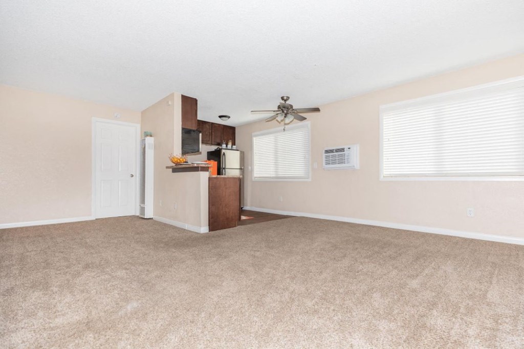 an empty living room with carpet and a ceiling fan