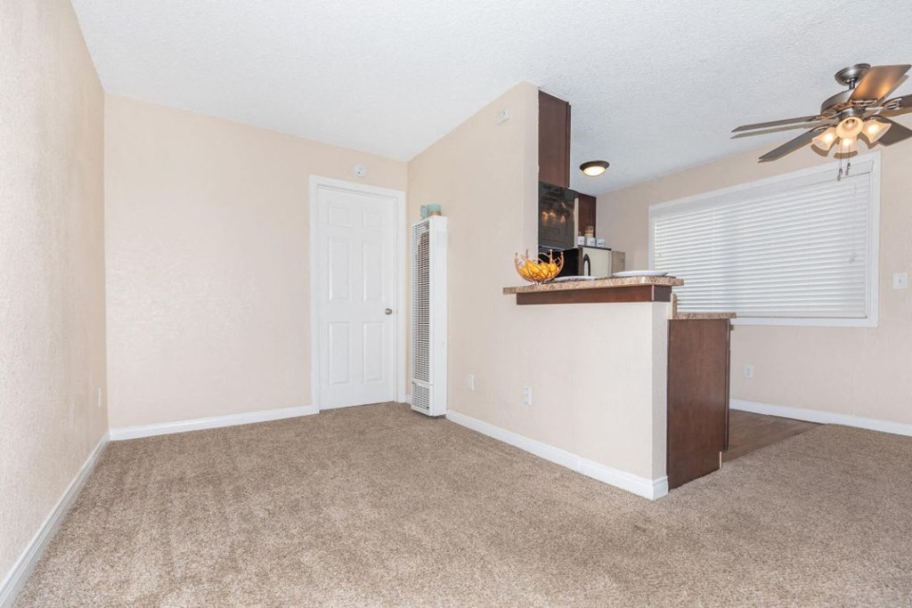 an empty living room and kitchen with a ceiling fan