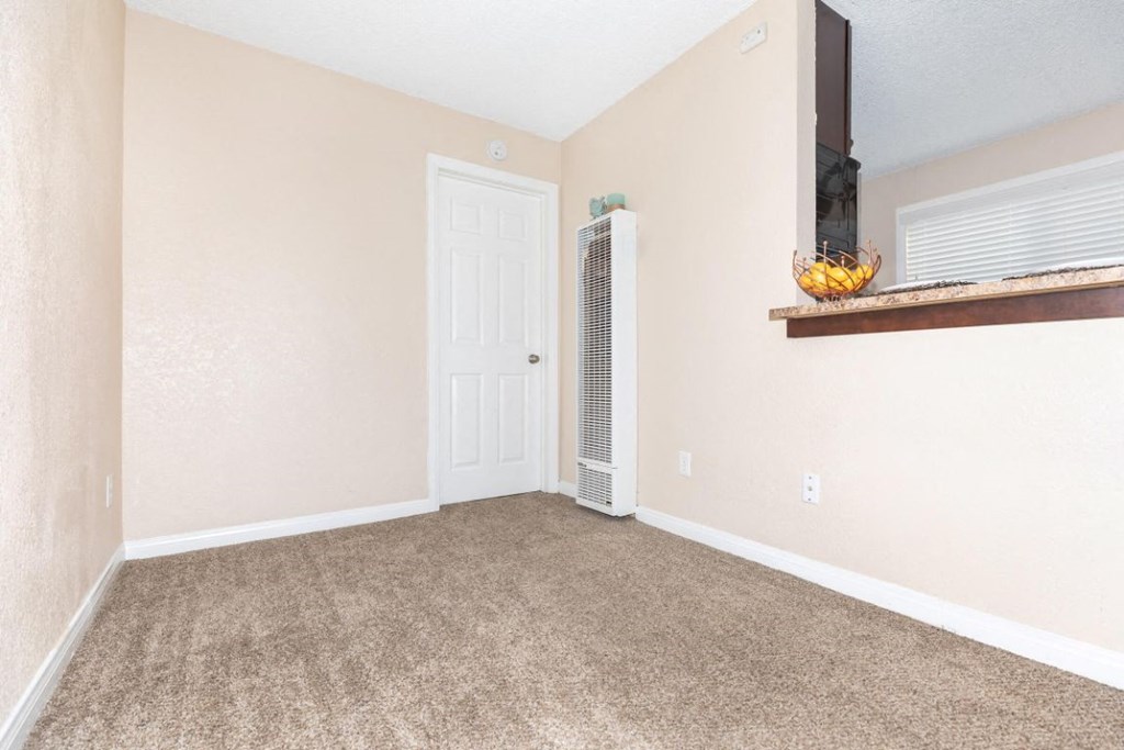 an empty living room with a heater and a door