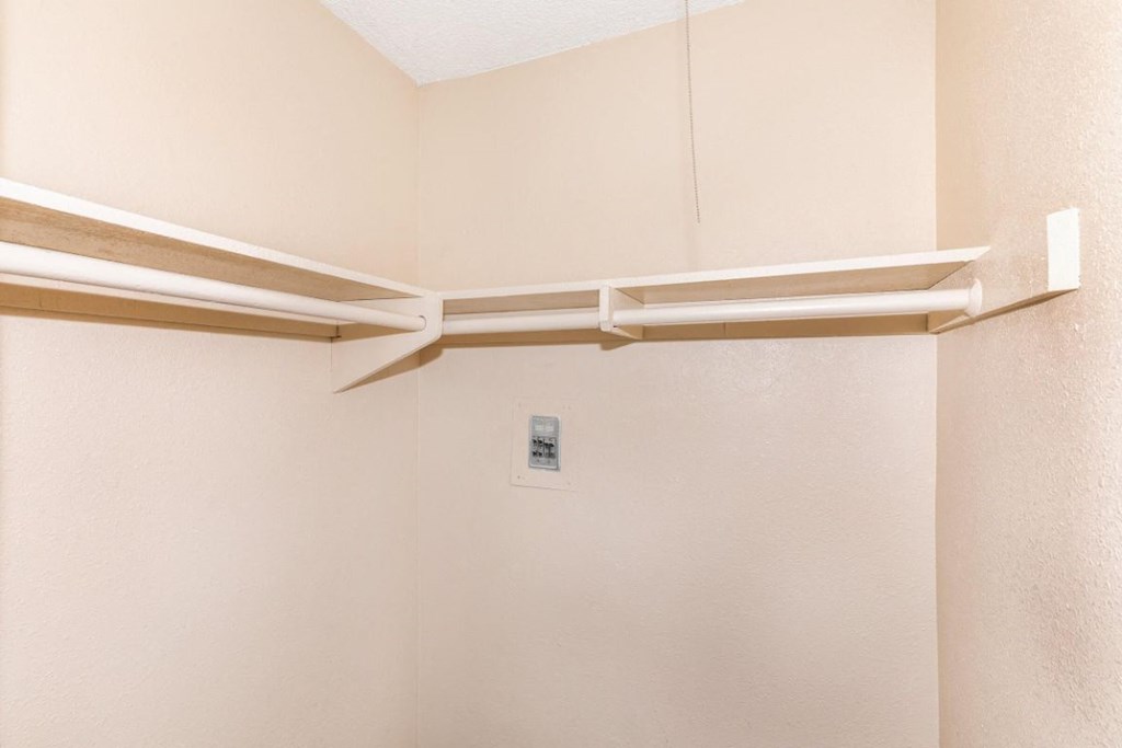 a walk in shower in a bathroom with white walls and a white shelf