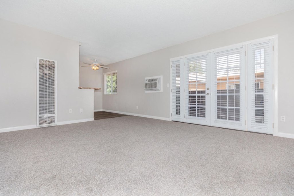 an empty living room doors to a kitchen
