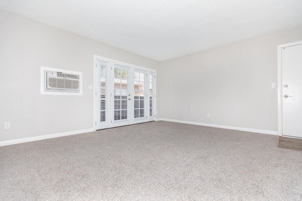 an empty living room with a door to a balcony