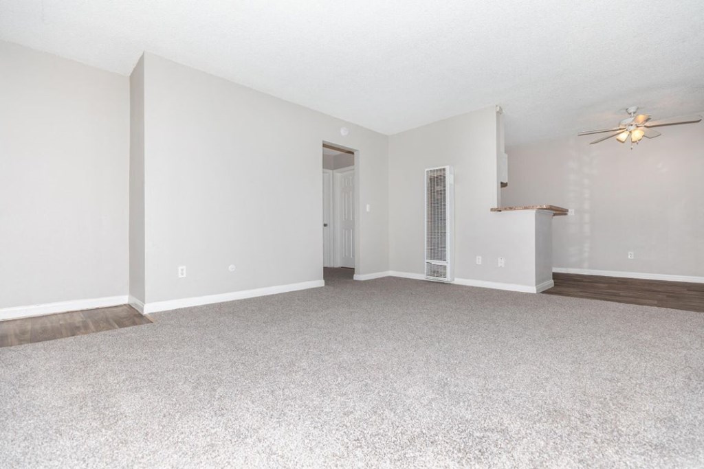 an empty living room with white walls and a ceiling fan