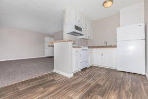 an empty kitchen with white cabinets and a wood floor