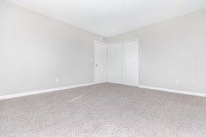 an empty living room with white carpet and a door