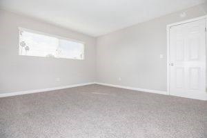 an empty room with a white door and a window