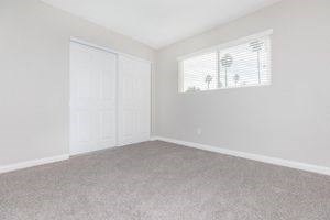 an empty bedroom with white walls and a window