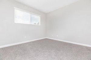 an empty bedroom with a window and a carpeted floor