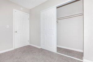 an empty bedroom with two doors and a closet