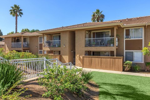 A sunny day at a row of apartment buildings with green lawns and palm trees.