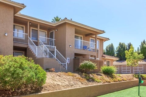 A two-story apartment building with a balcony and staircase.
