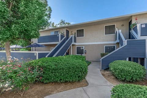 an apartment building with stairs and bushes and trees