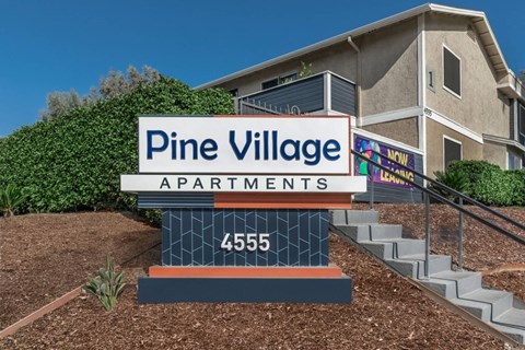 a sign for pine village apartments in front of a building