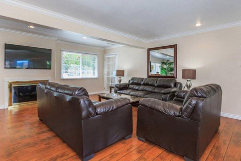 Two black leather sofas in a living room with a television and fireplace.