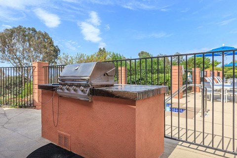 A red brick BBQ grill with a black grill grate and a black handle.
