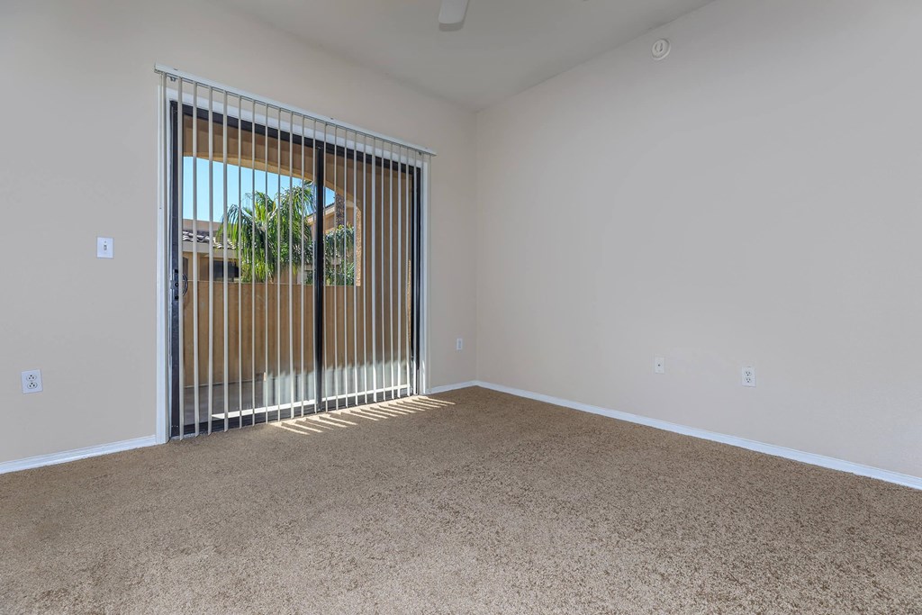 an empty living room with blinds and a door to a patio