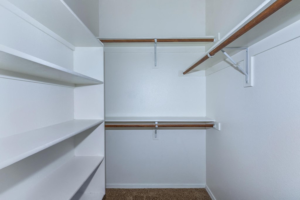 a walk in closet with white walls and shelves