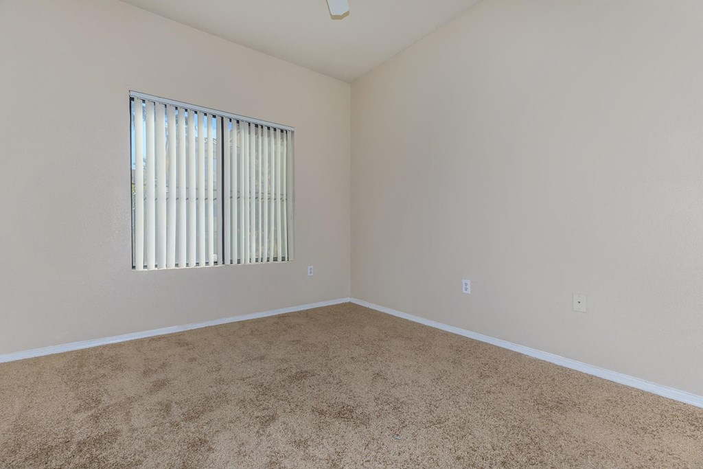 an empty room with a window and carpet