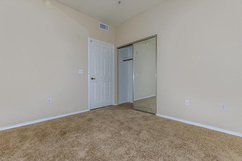 a bedroom with a door to a closet and a carpeted floor