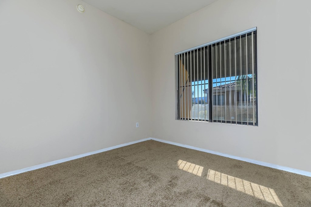 an empty living room with a window and carpet