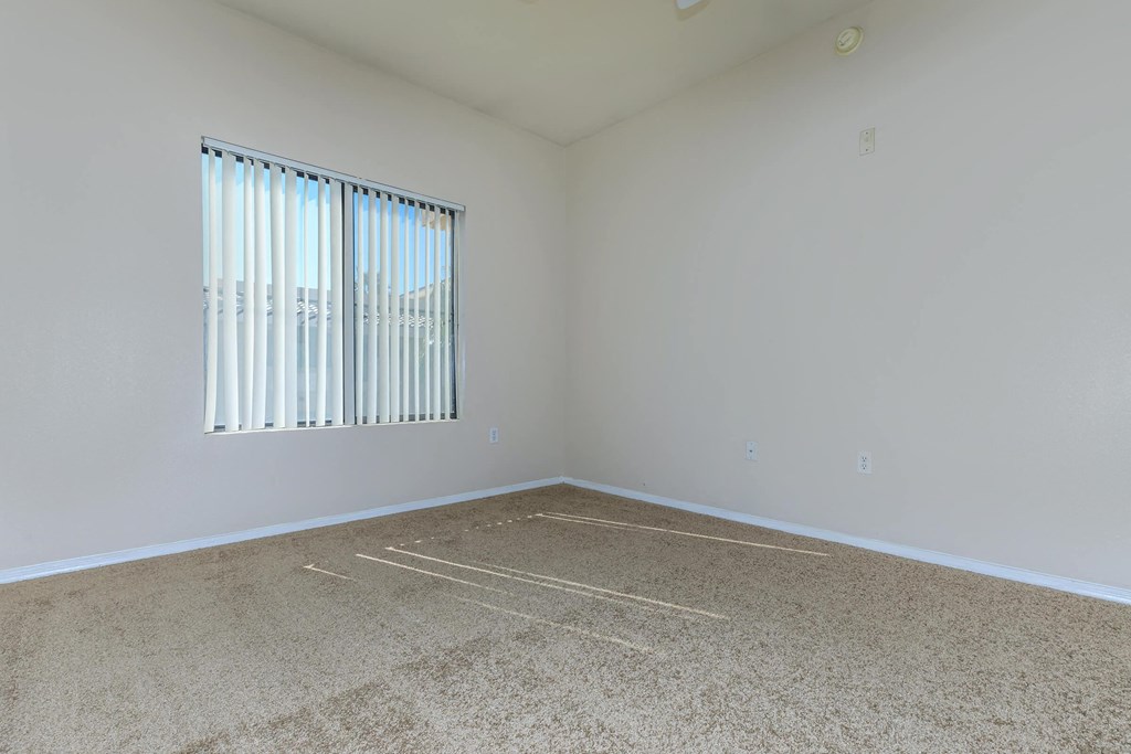 an empty room with a window and carpet