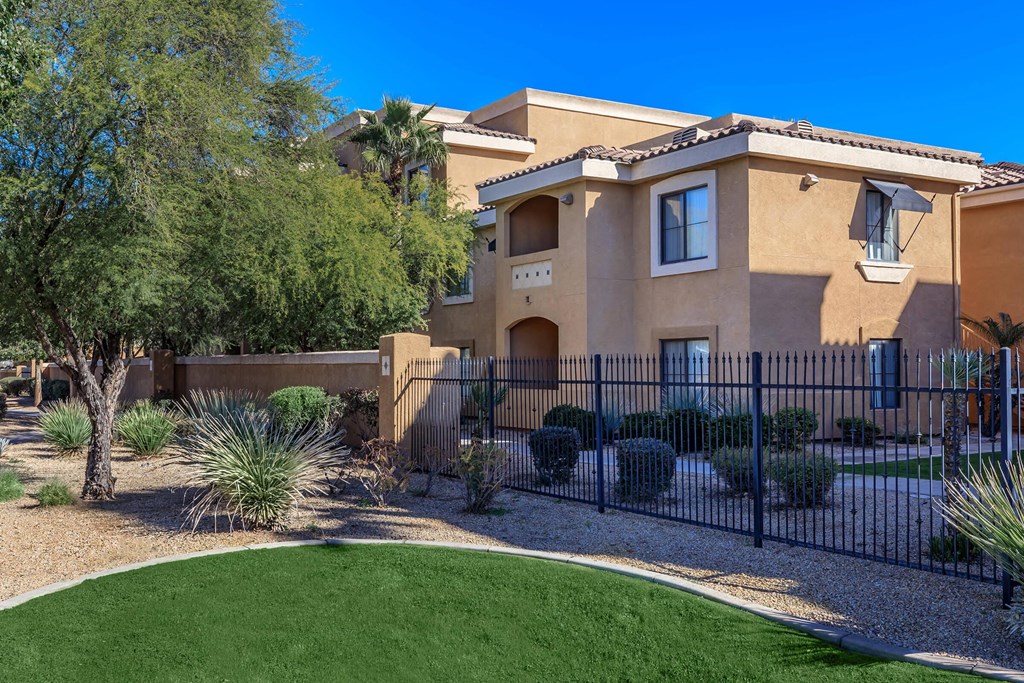 a house with a fence and a lawn in front of it