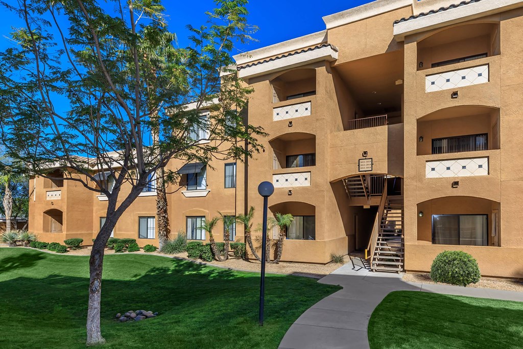 a building with a sidewalk in front of it and green grass