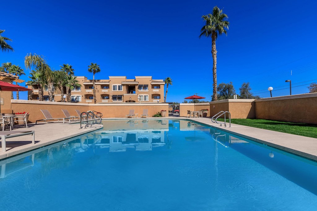 a swimming pool with palm trees and a building in the background