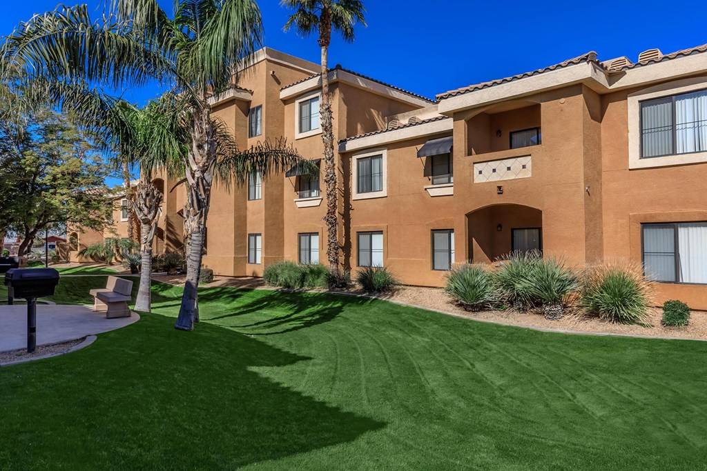 an apartment building with a green lawn and palm trees