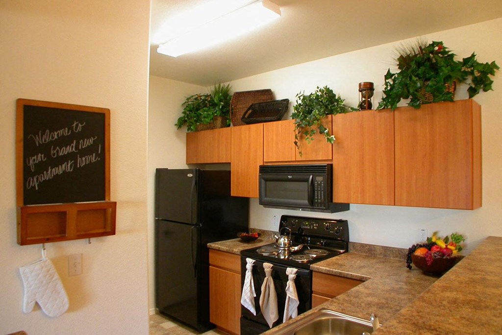 a kitchen with black appliances and a chalkboard on the wall
