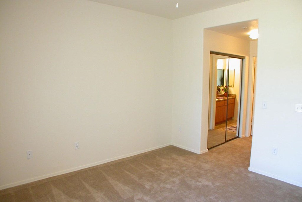 an empty living room with a mirror in the bathroom