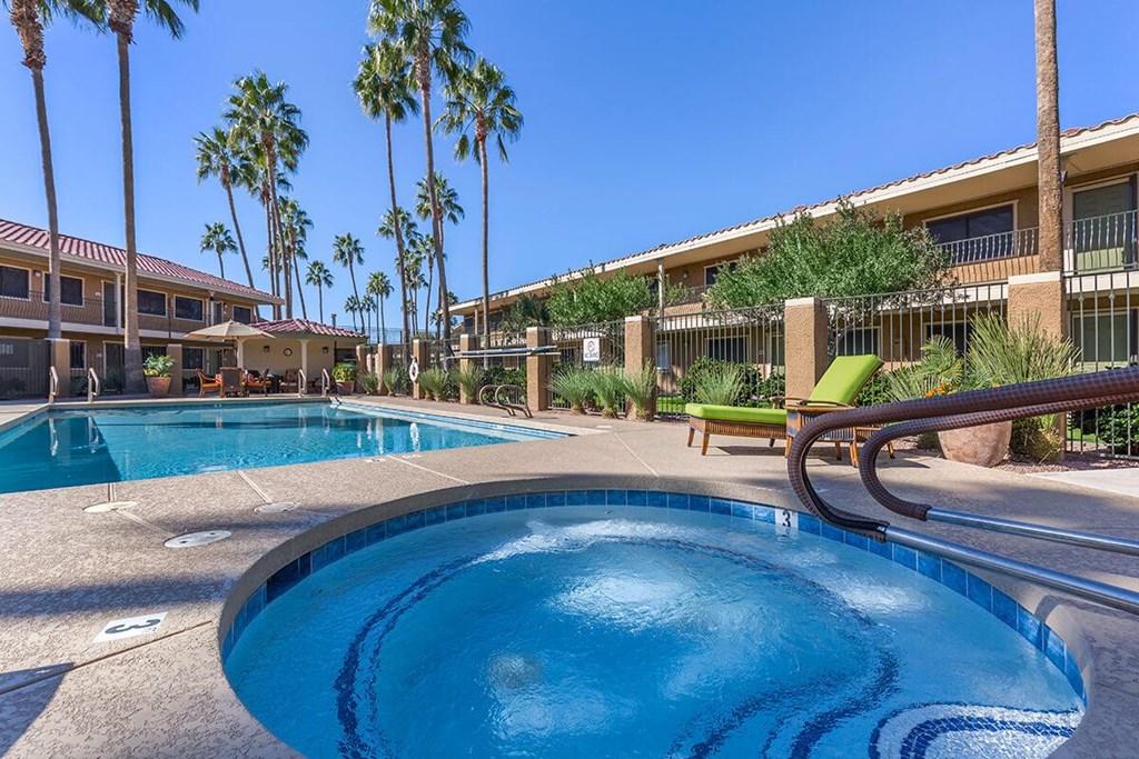 a large swimming pool with a hot tub in front of a resort building