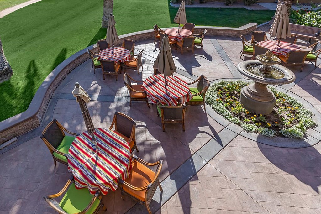 a patio with tables and chairs and a fountain