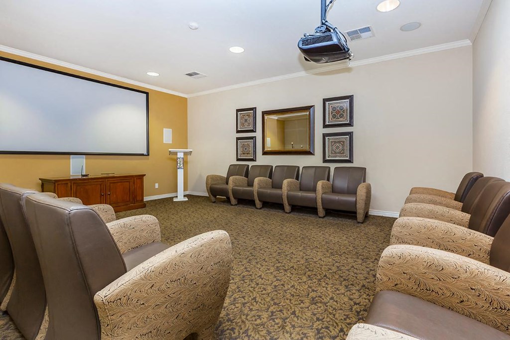a meeting room with a projector screen and chairs