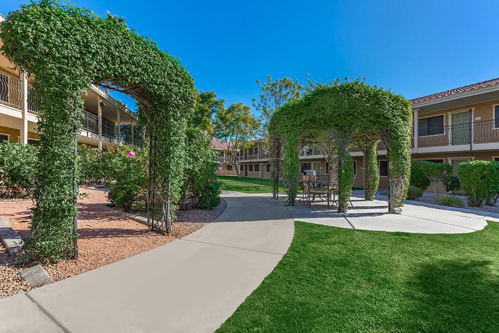 a walkway with two archways covered in ivy