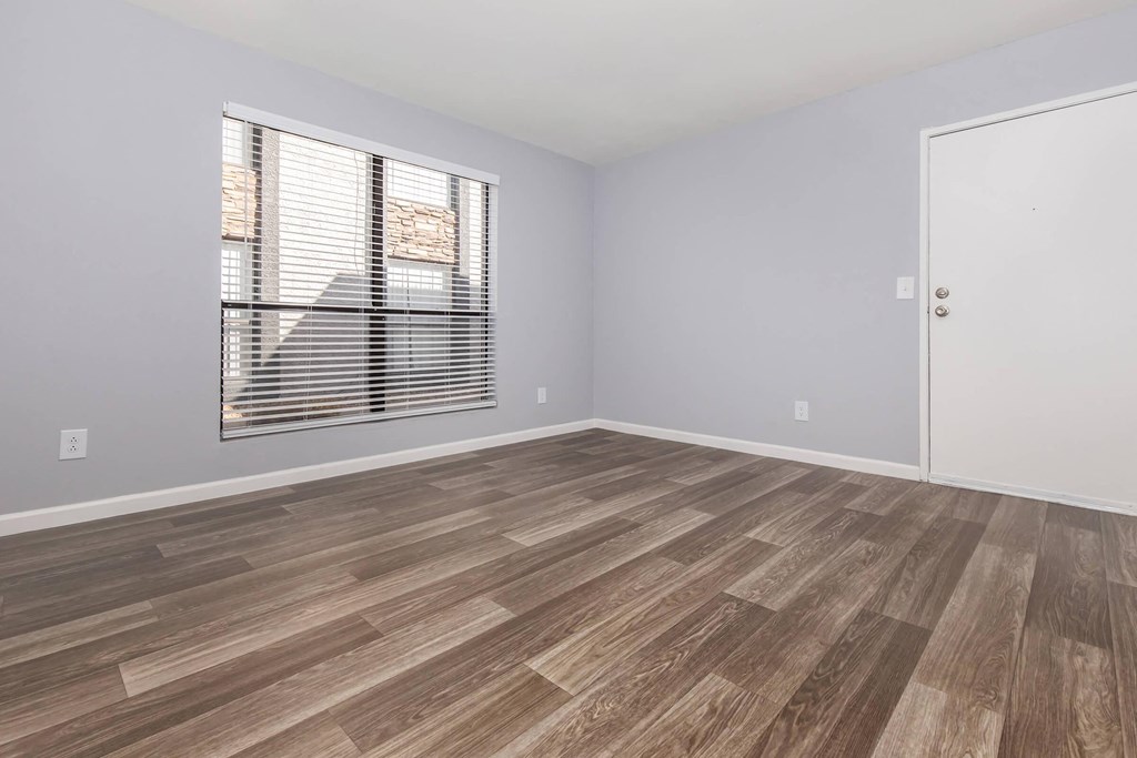 an empty room with a window and wood flooring