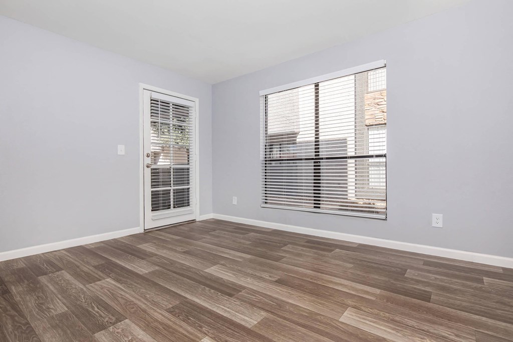 an empty living room with a large window and wood flooring