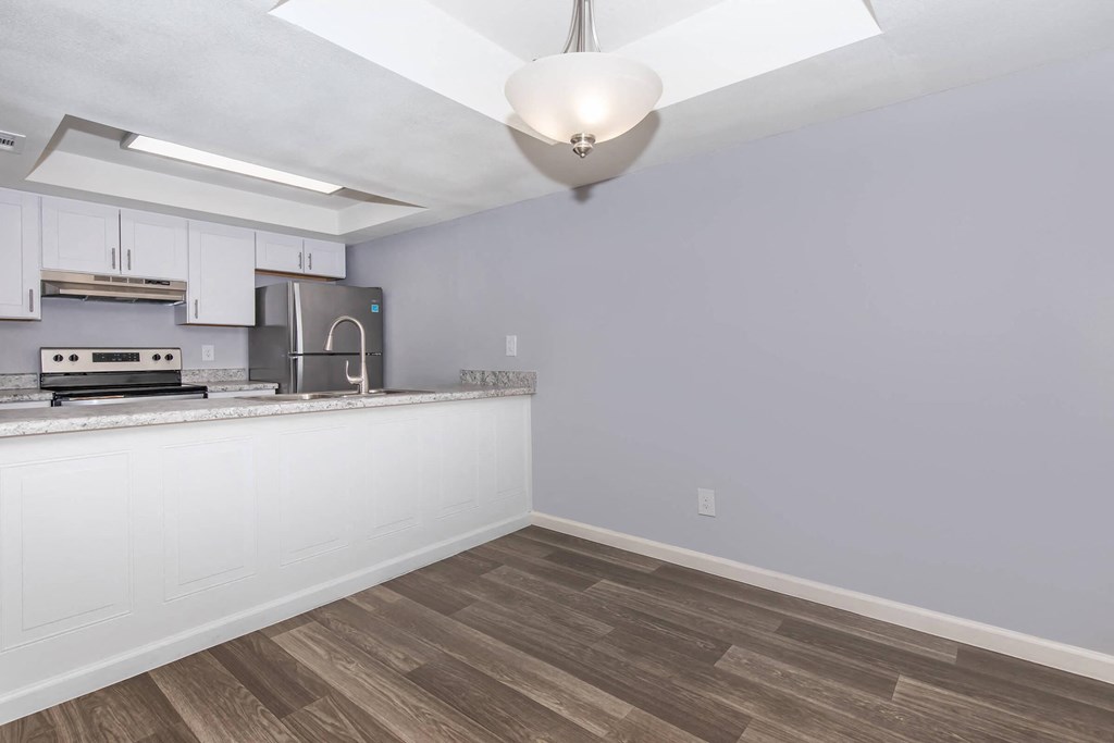 an empty kitchen with white cabinets and a counter top