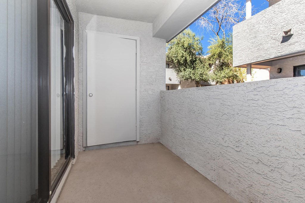 a corridor with a white wall and a door to a balcony