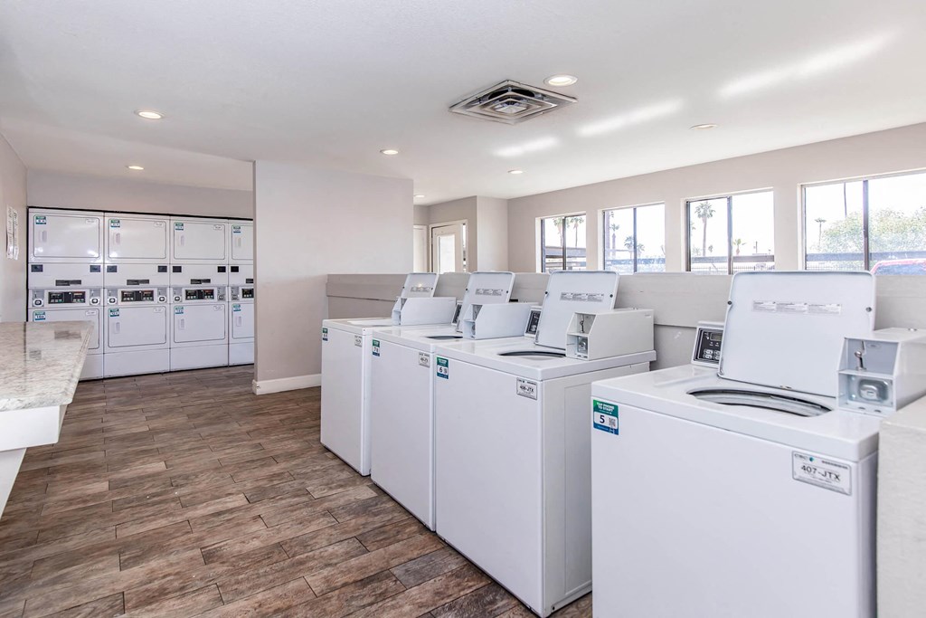 a group of washers and dryers in a laundry room with machines