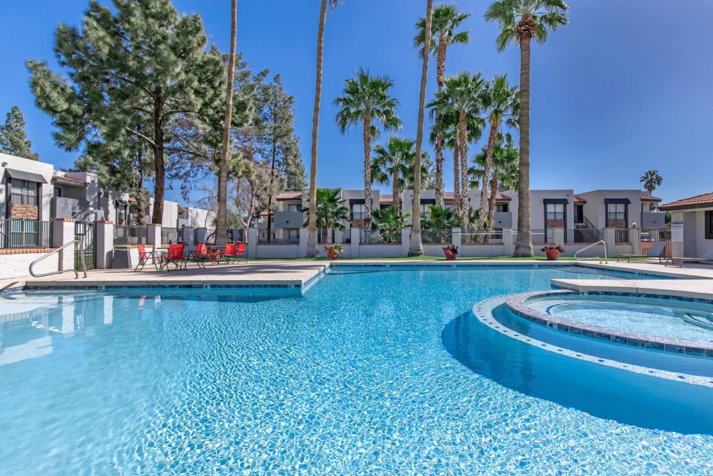 a large swimming pool with palm trees and apartments in the background