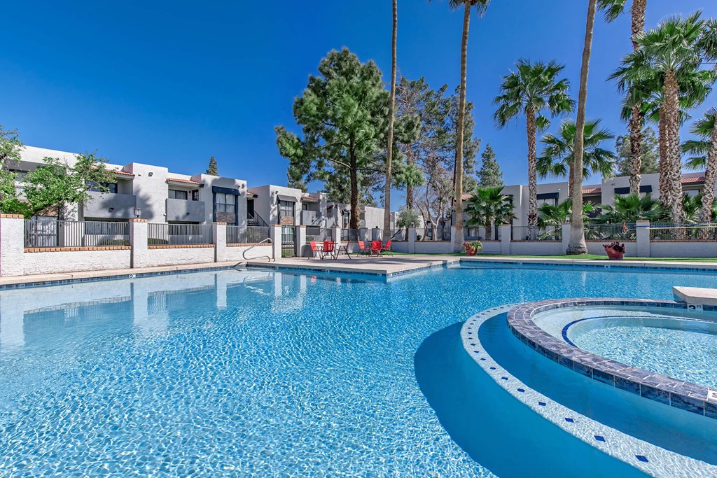 a large swimming pool with palm trees and apartments in the background