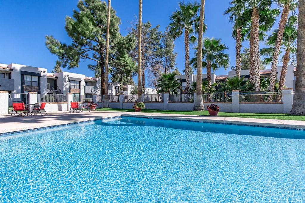 a large swimming pool with palm trees and apartments in the background