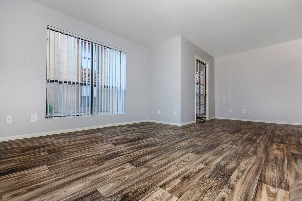 an empty living room with wood flooring and a window